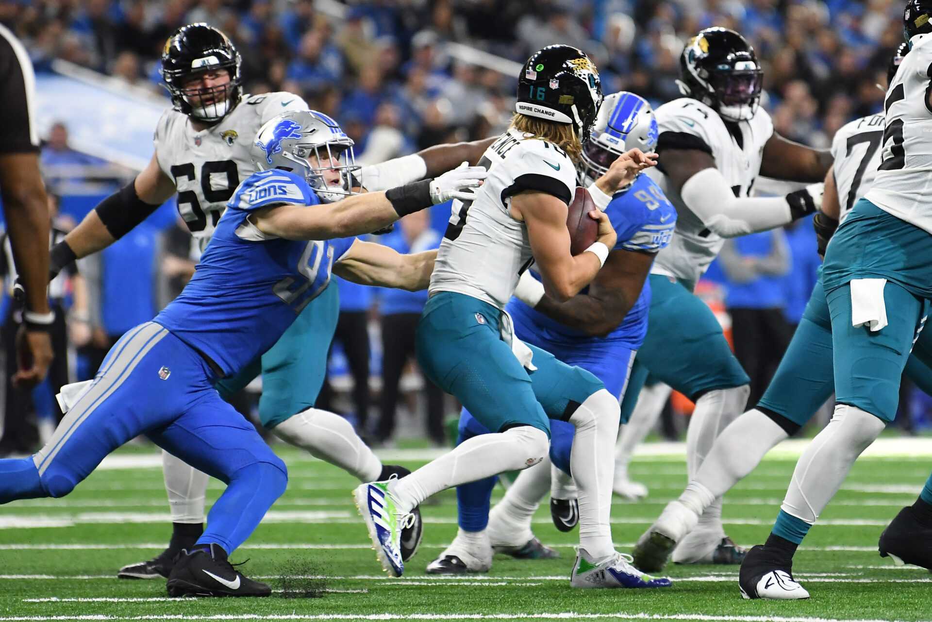 Dressed all in blue, Detroit Lions defensive end Aidan Hutchinson gets his hands on Jacksonville Jaguars quarterback Trevor Lawrence behind the line of scrimmage