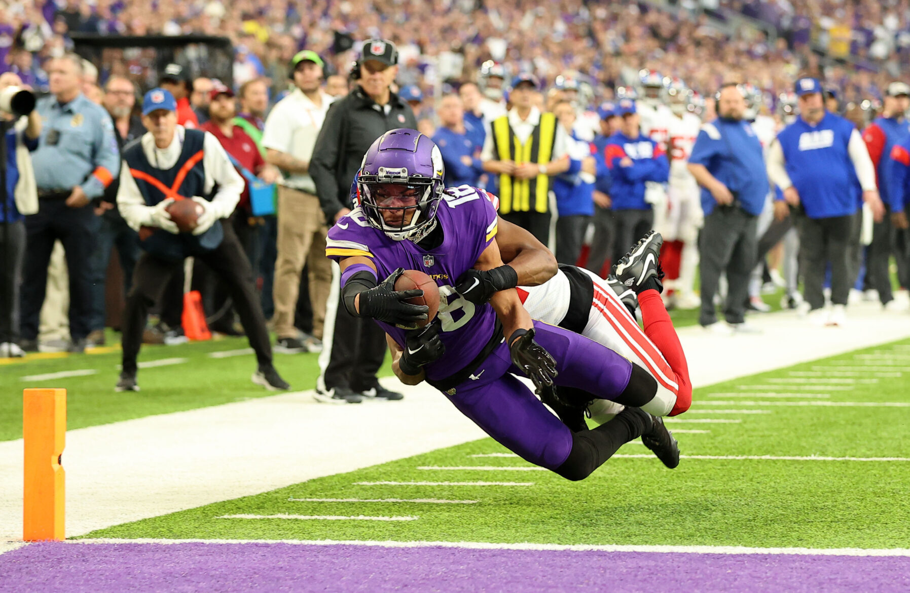 Minnesota Vikings wide receiver Justin Jefferson, in a purple uniform, lunges into the endzone