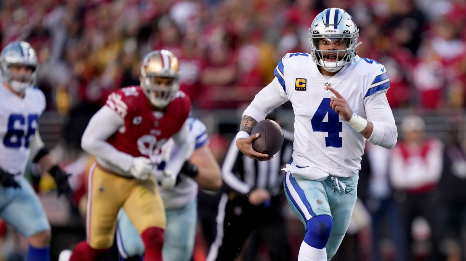 Dallas Cowboys quarterback Dak Prescott (in a white jersey and silver helmet and pants) runs away from San Francisco 49ers defenders