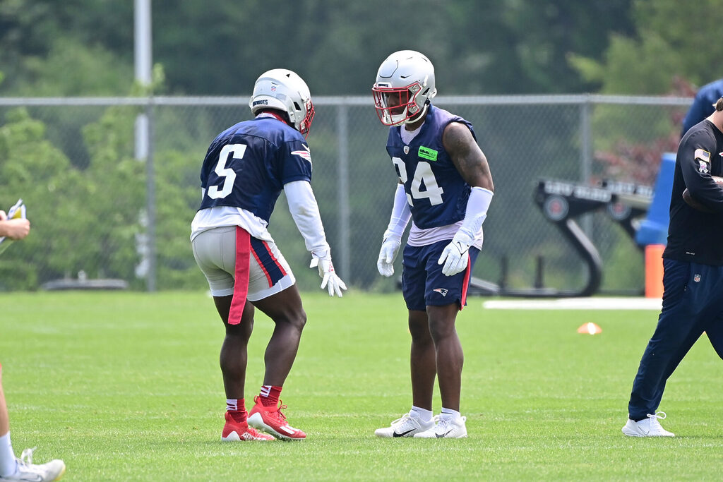 Two Patriots players in dark blue jerseys and silver helmets square up to run a drill.