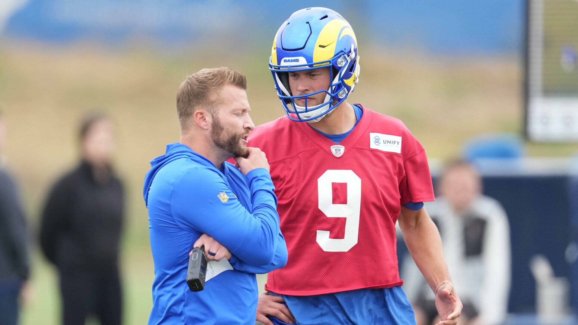Los Angeles Rams head coach Sean McVay and quarterback Matthew Stafford, in a red practice jersey, talk on the sideline of the team's minicamp.