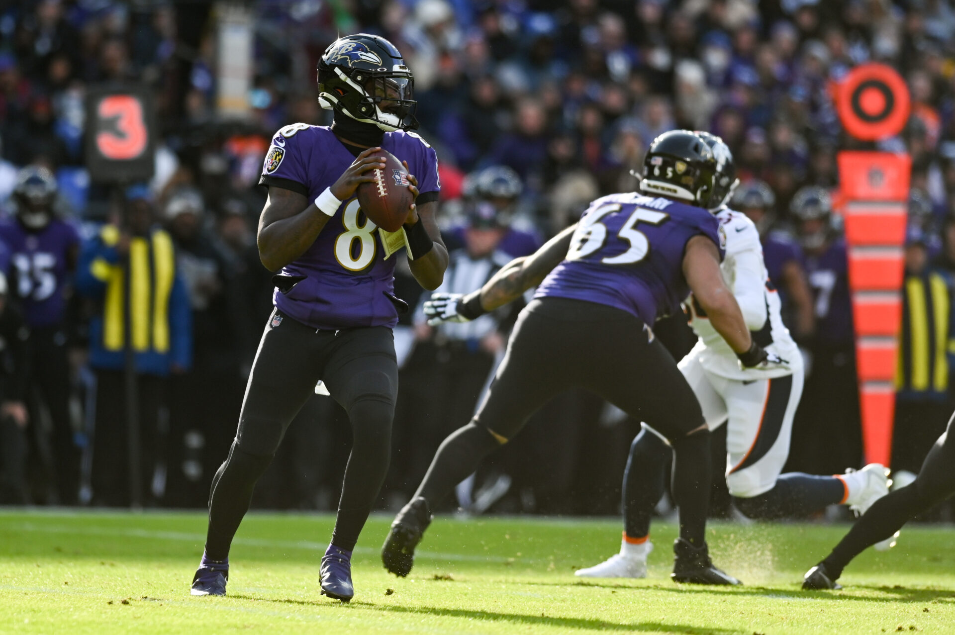 In a purple jersey and black pants, Baltimore Ravens quarterback Lamar Jackson drops back for a pass