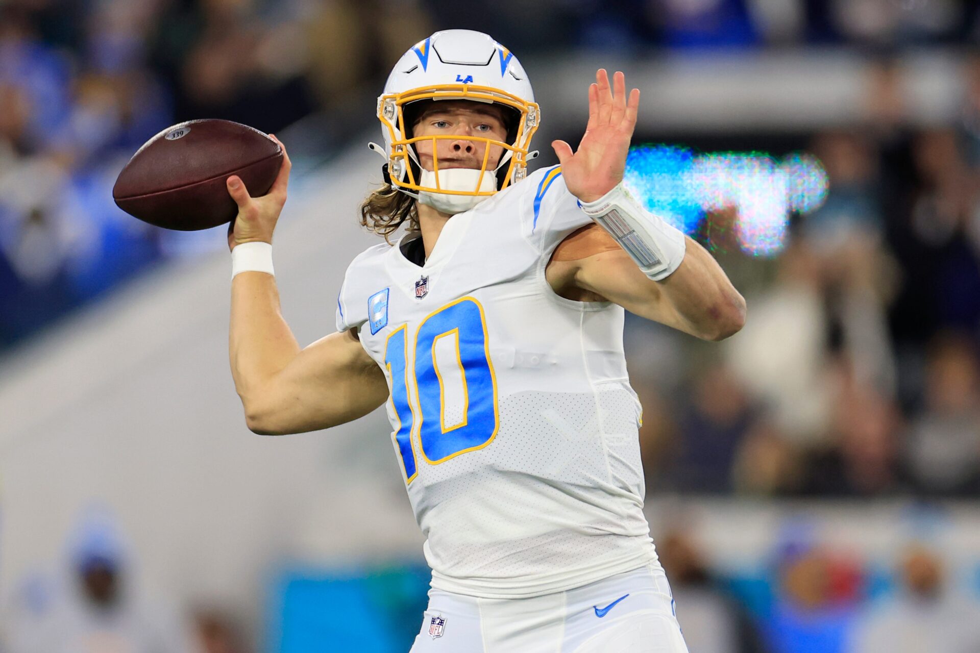 A cropped, upper-body image of Los Angeles Chargers quarterback Justin Herbert throwing a pass. He's in an all-white uniform