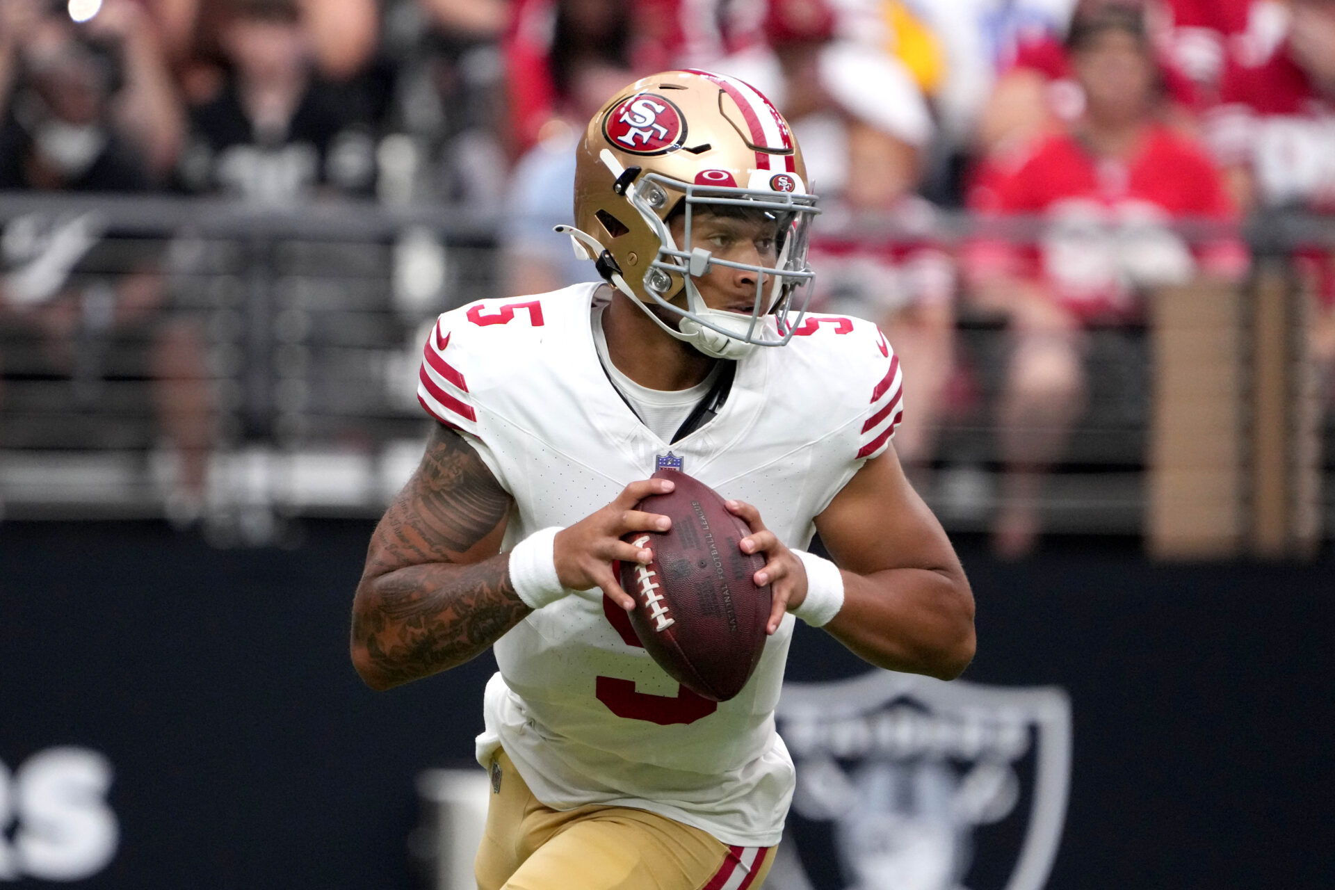 Upper-body image of Trey Lance holding a football while moving around in the pocket