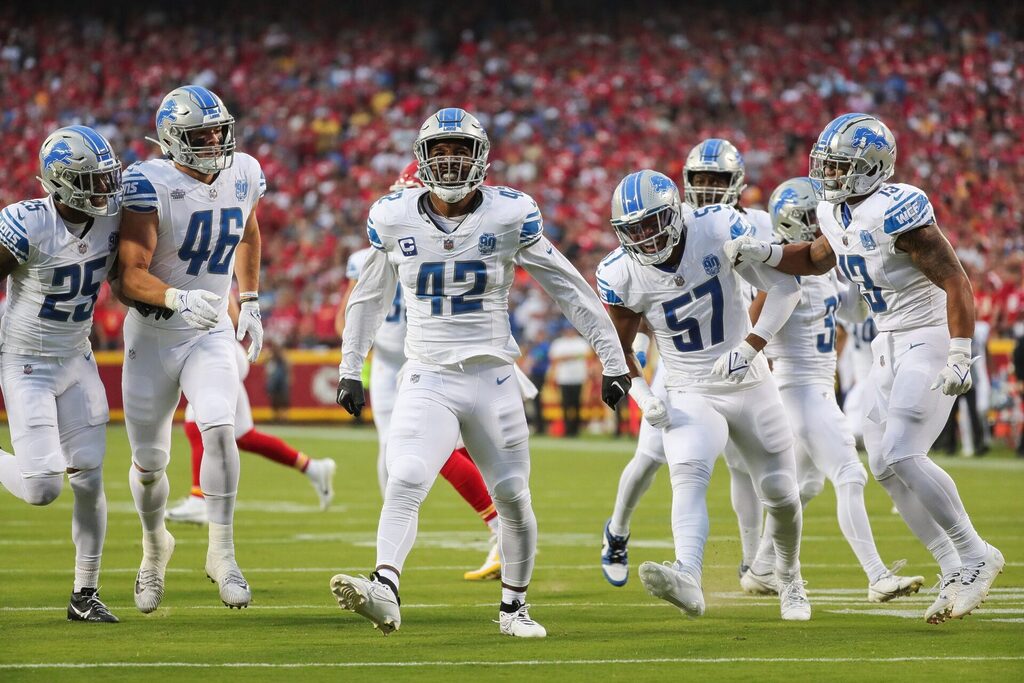 Detroit Lions players, led by linebacker Jalen Reeves-Maybin celebrate against the Kansas City Chiefs. The Lions players are in white jerseys and pants and have silver helmets