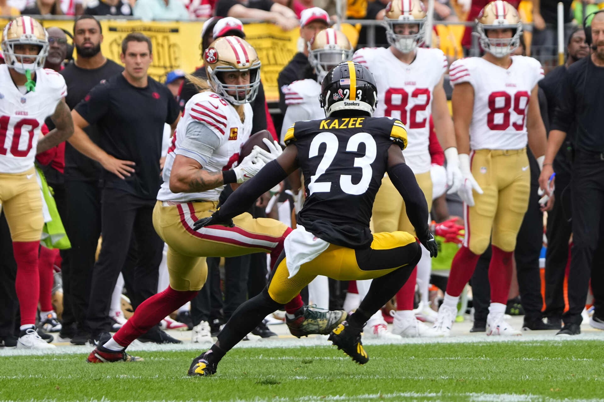 In front of the 49ers sideline, George Kittle tries to cut around Steelers defender Kazee, who has his back to the cameraperson 