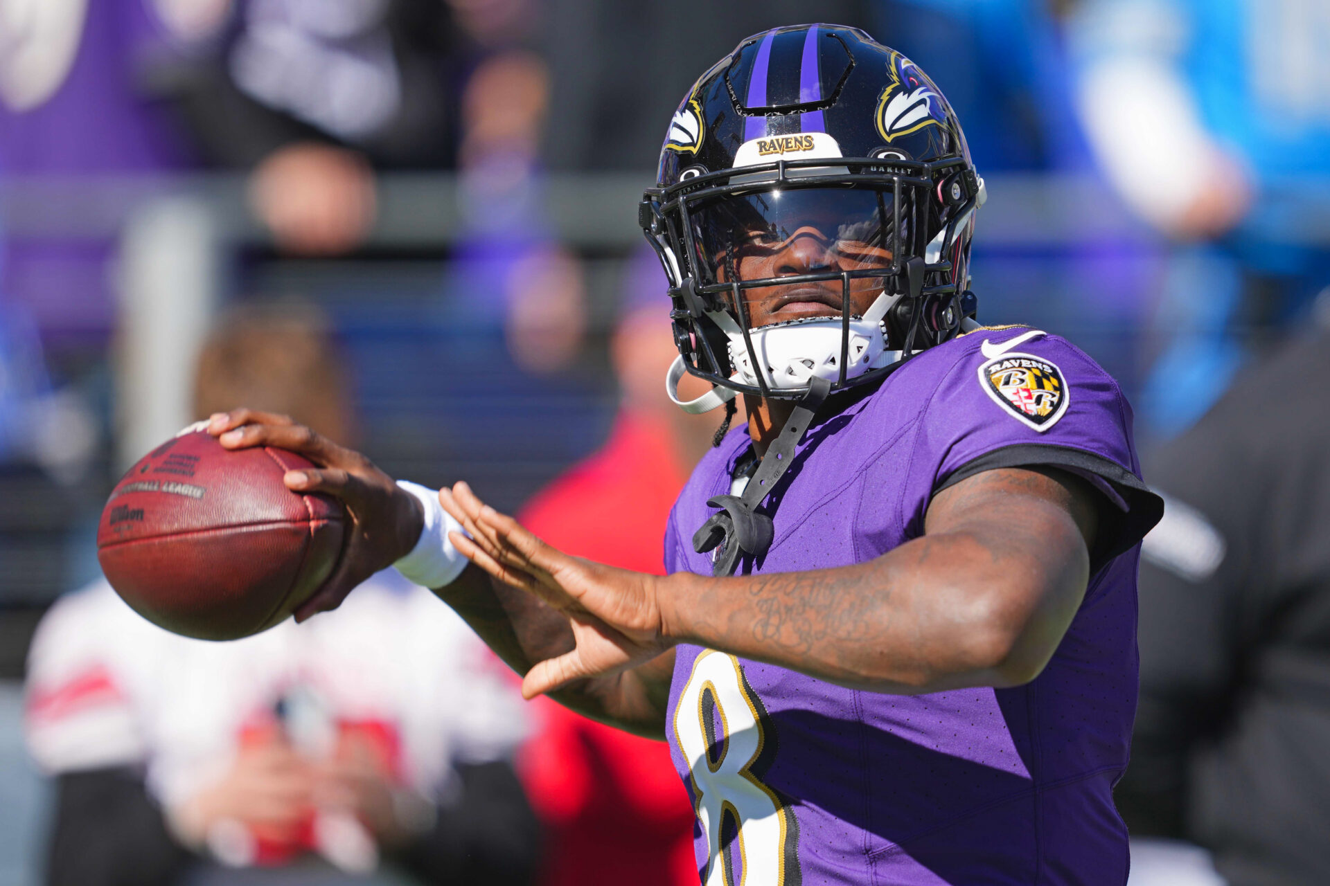 Close-up image of Lamar Jackson (wearing a purple jersey) in the middle of his throwing motion