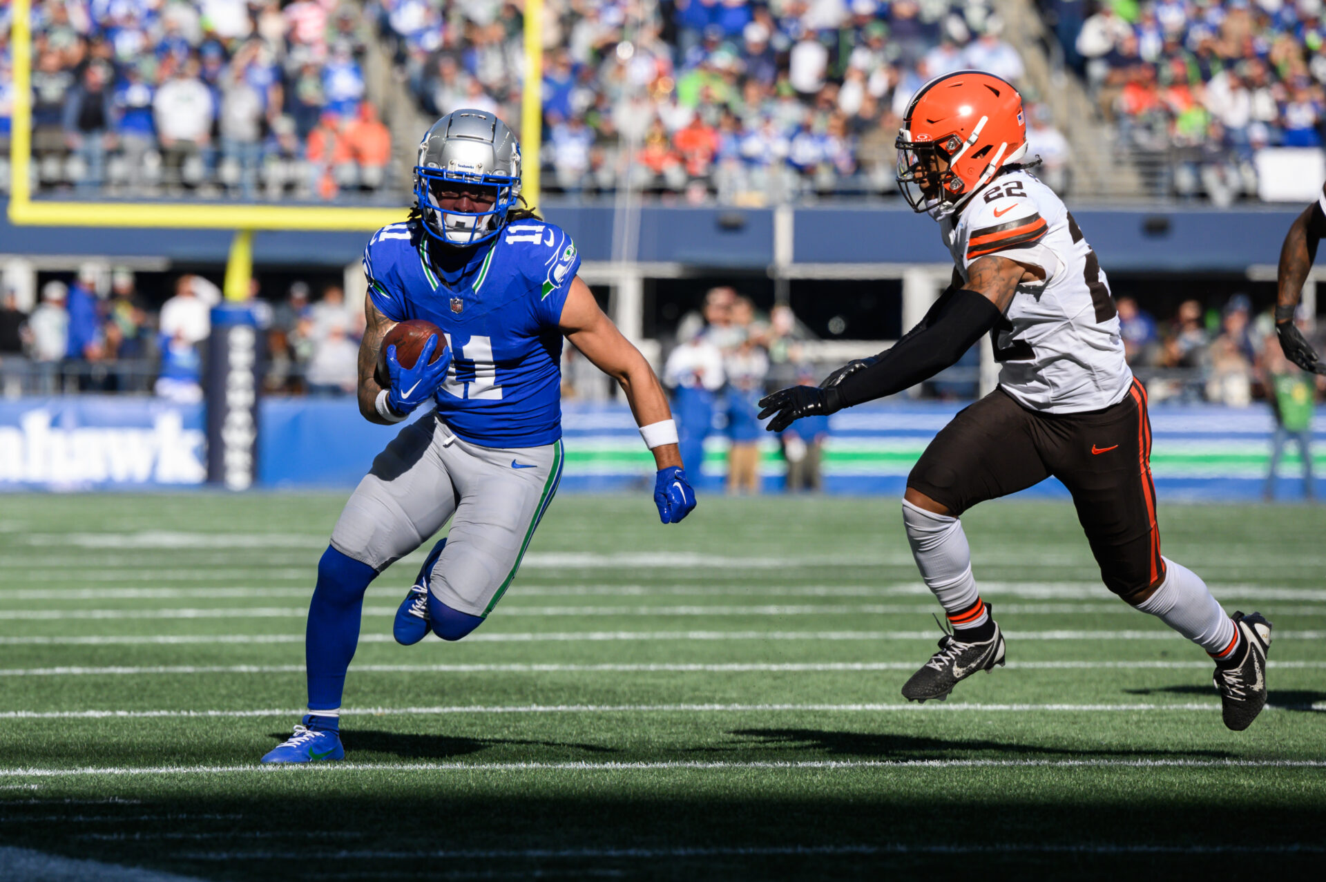 Jaxon Smith-Njigba runs with the ball as a Cleveland Browns defender closes in on him