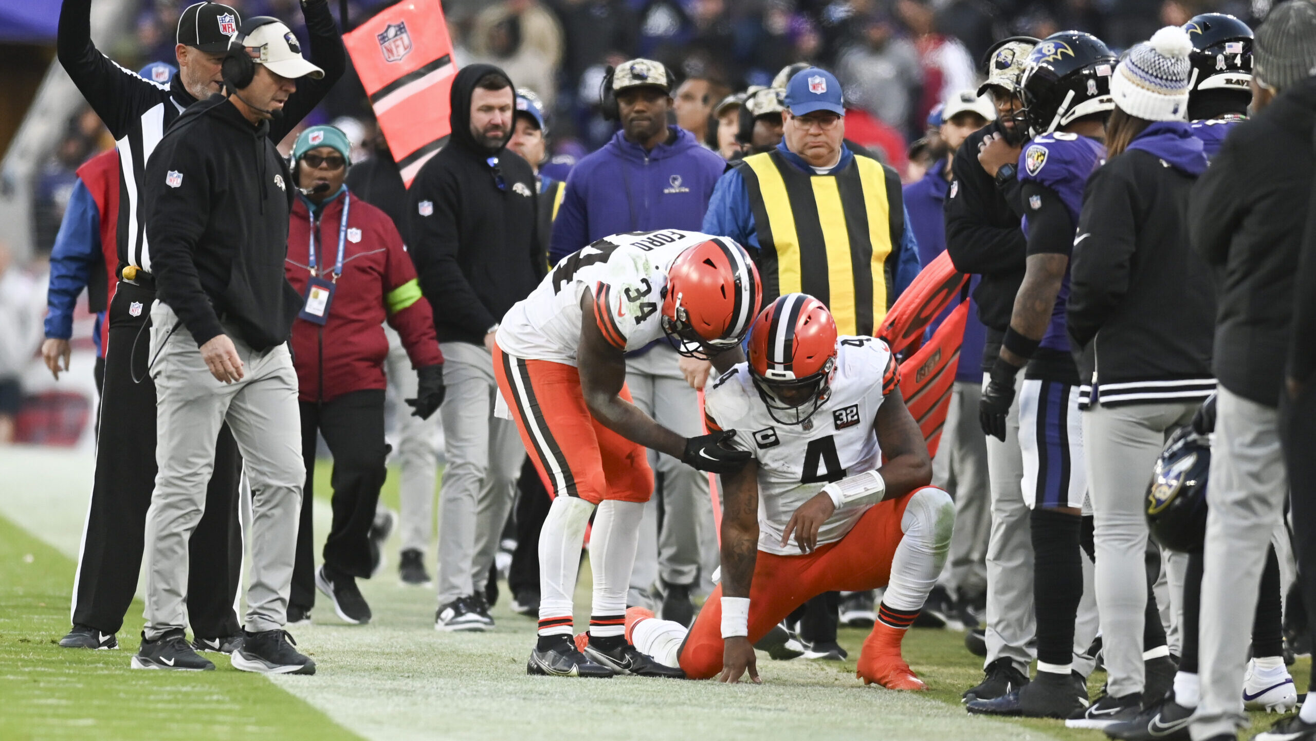 Deshaun Watson crouches injured on the Ravens' sideline