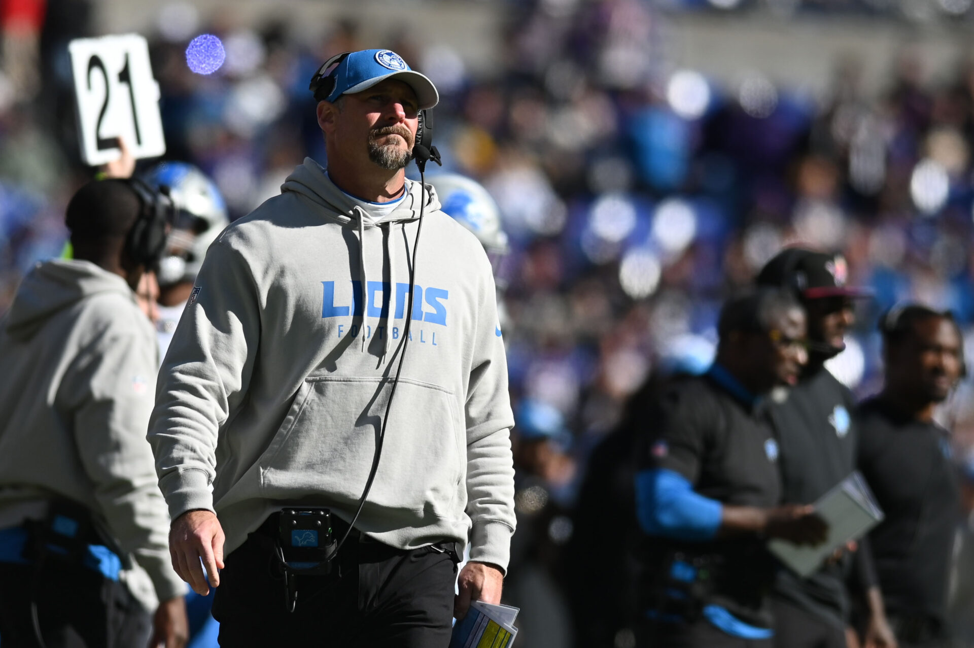 Dan Campbell stands on the sideline in a Lions sweatshirt
