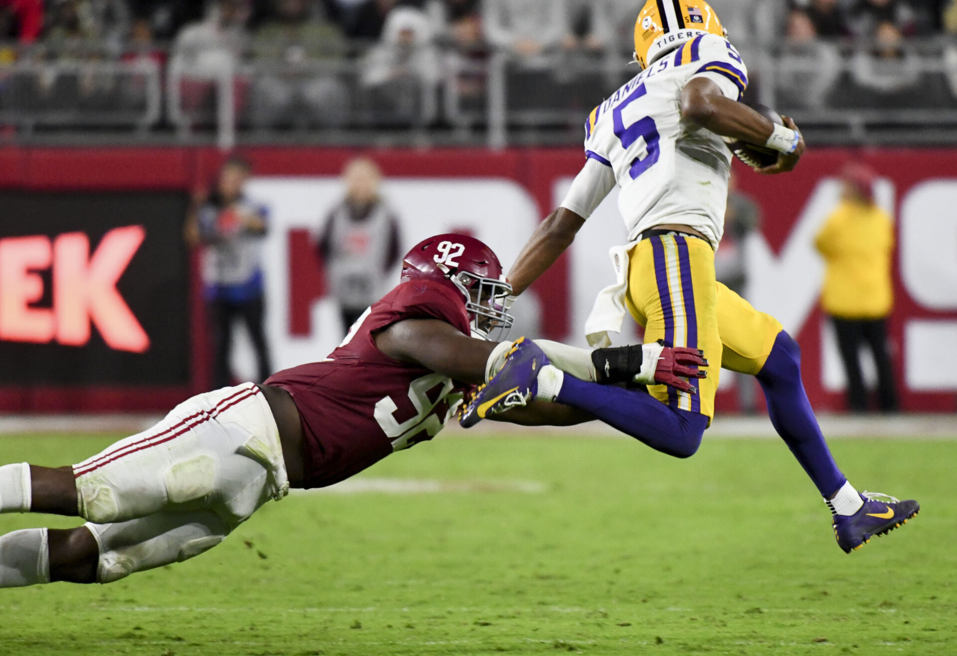LSU QB Jayden Daniels runs while an Alabama defender reaches out to stop him