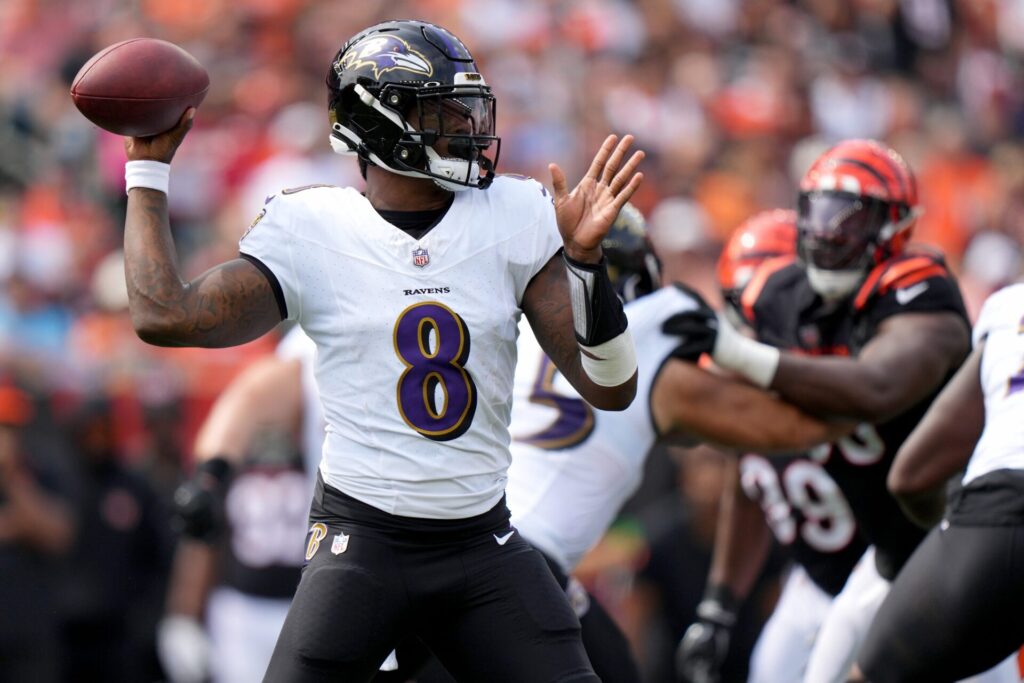 Lamar Jackson, in a white Ravens jersey, throws the ball in the pocket against the Browns