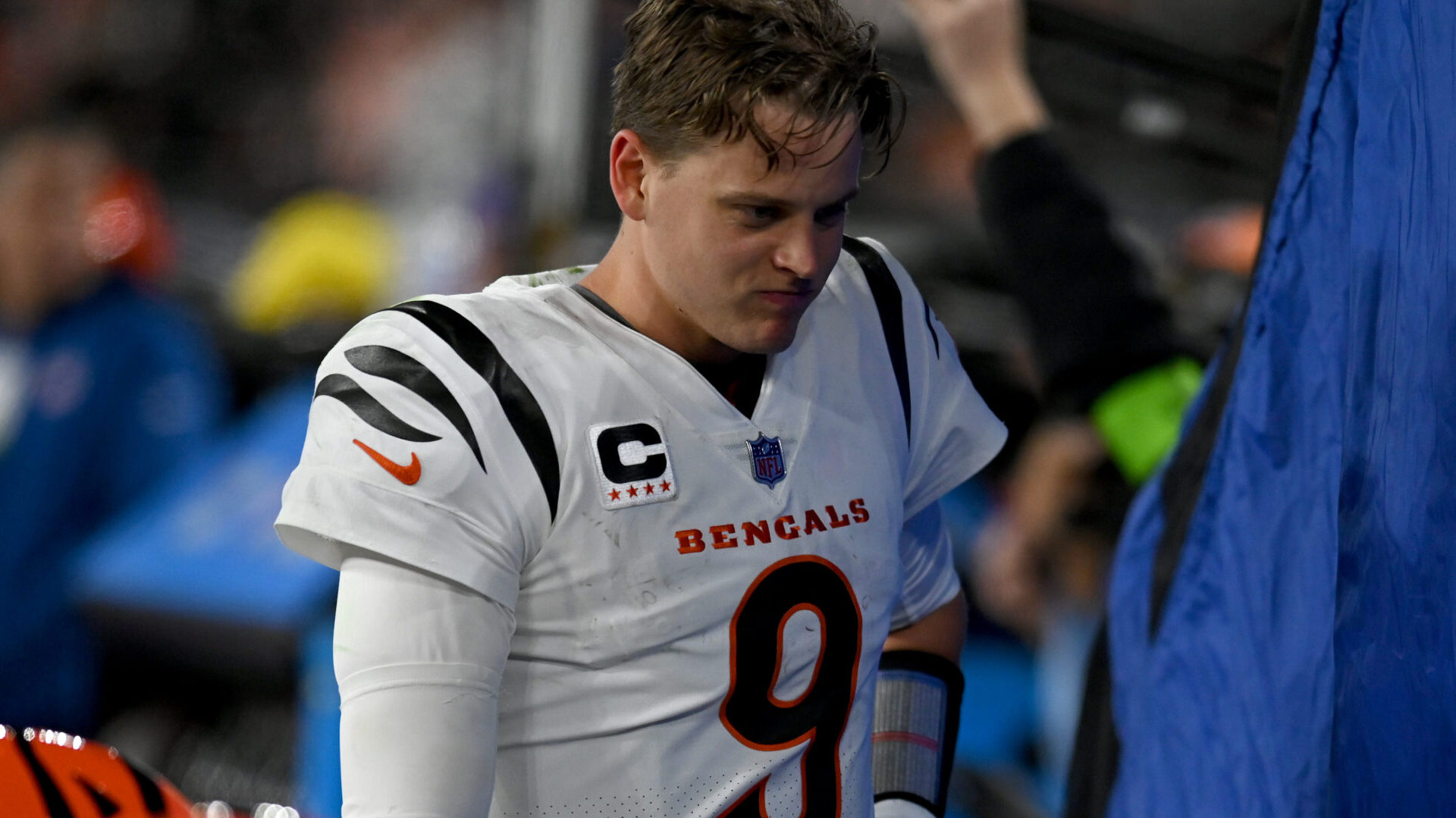 Joe Burrow looks downcast on the sideline next to the team tent without his helmet on