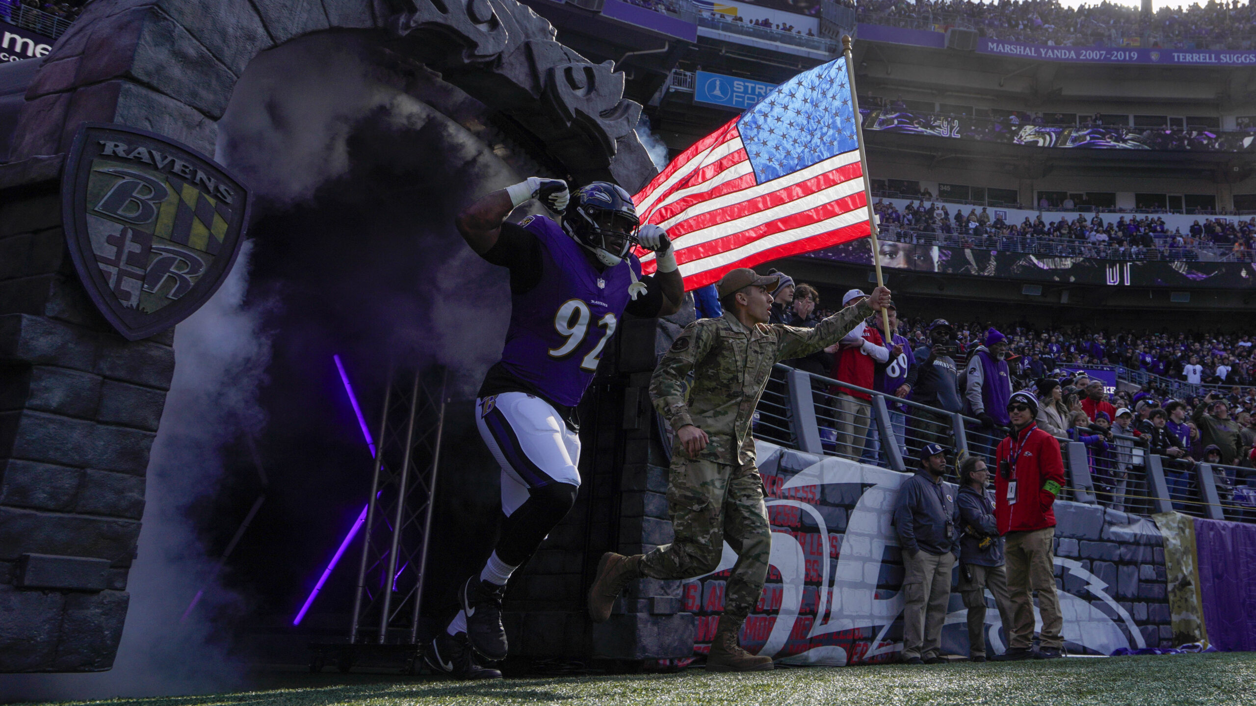 Baltimore Ravens defensive tackle Justin Madubuike (92) takes the field with a military service member before a game against the Cleveland Browns at M&T Bank Stadium