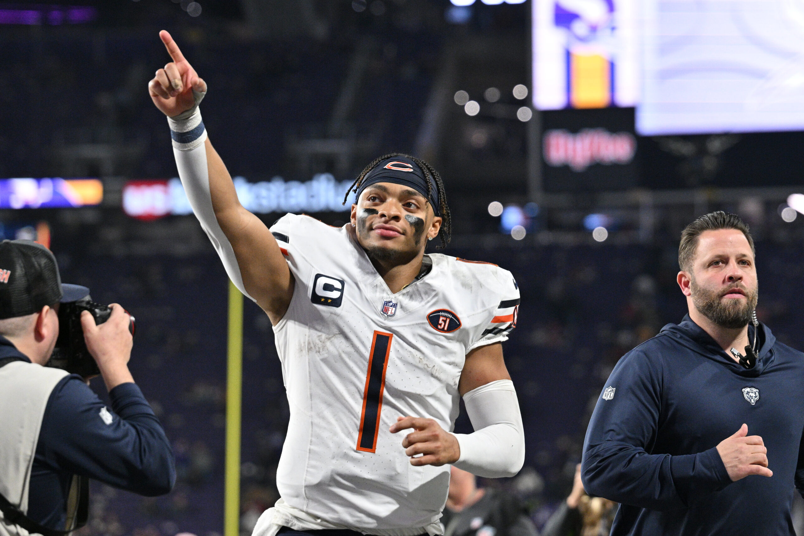 A helmetless Justin Fields points to the crowd as he walks off the field