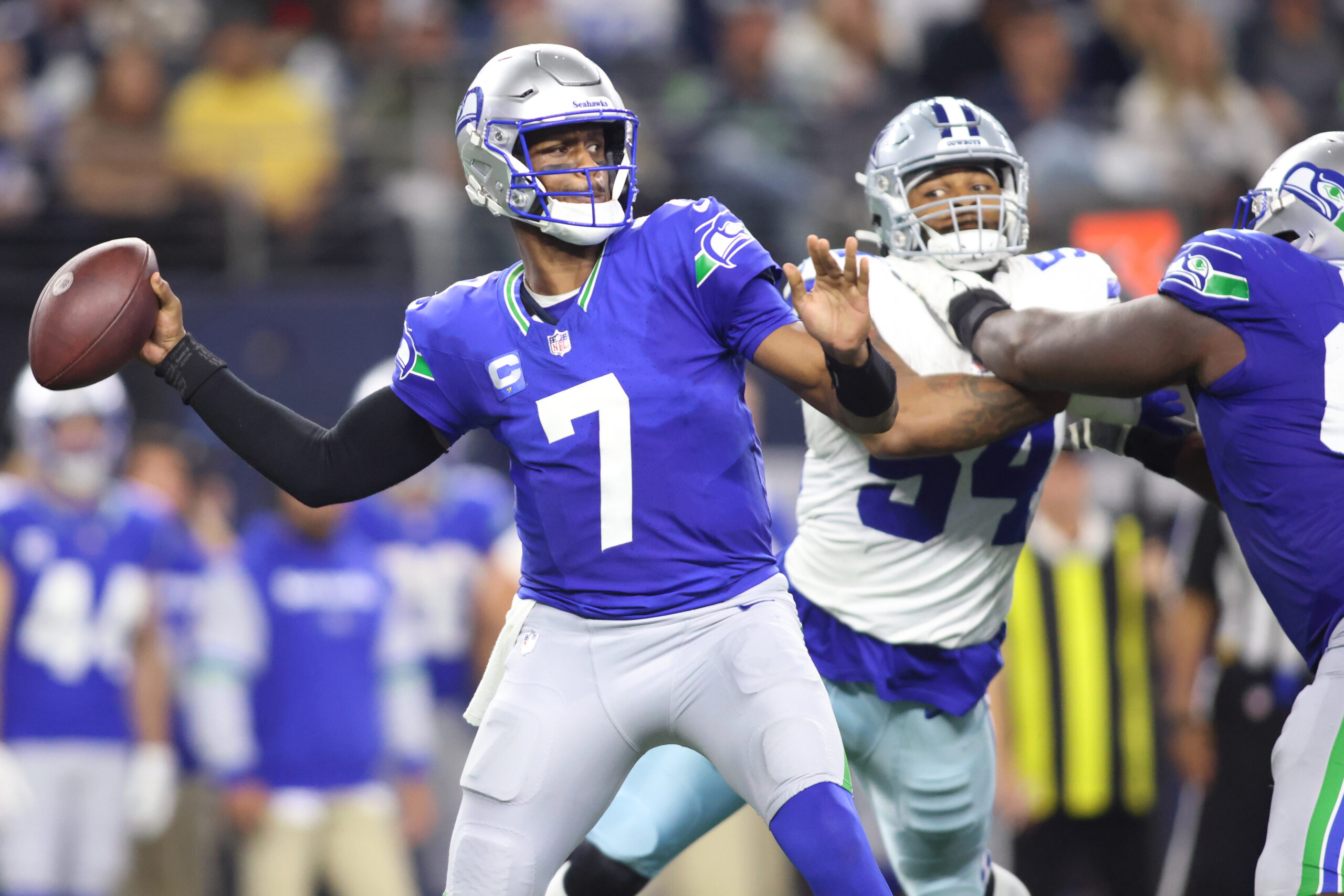 Geno Smith looks to pass as a Cowboys defender looks on