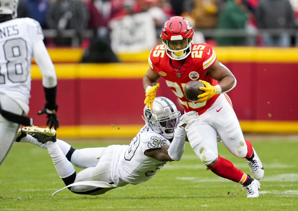 Clyde Edwards-Helaire runs the ball as a Raiders player tries to tackle him