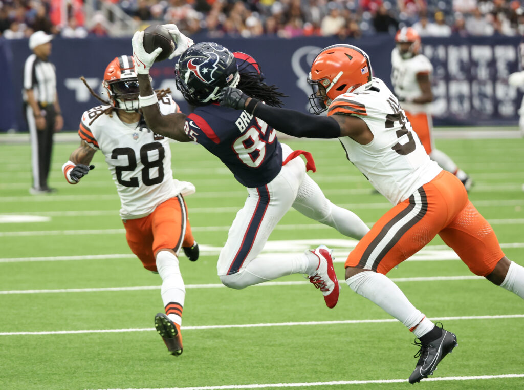 Noah Brown leaps sideways with a Browns defender behind him and another running toward him