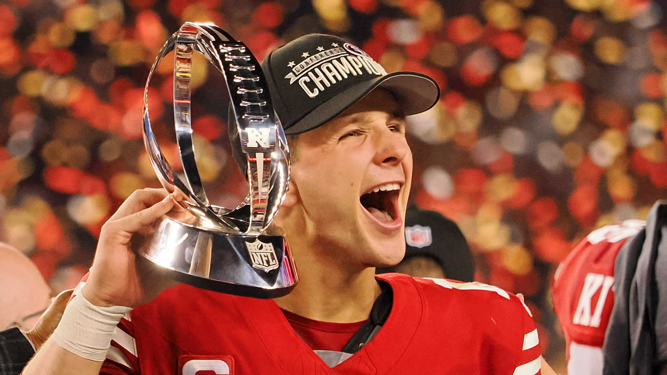 Brock Purdy celebrates while holding NFC Championship trophy.