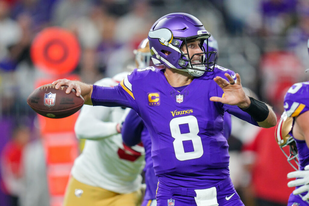 Kirk Cousins, in an all-purple uniform, drops back to throw a pass