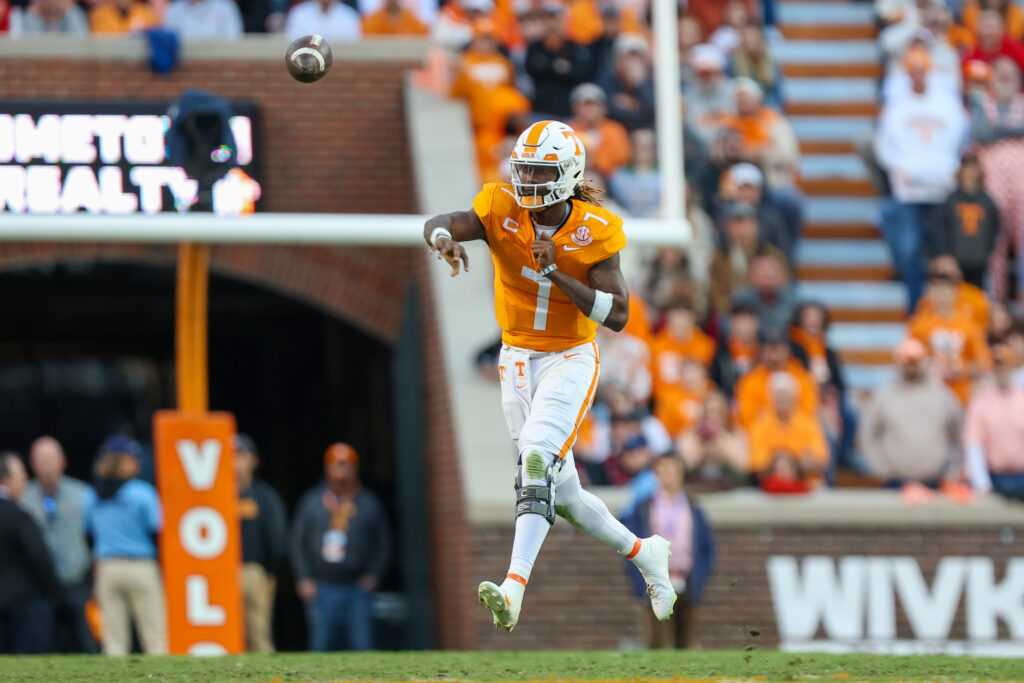 Joe Milton (in an orange jersey) throws the ball on the run; the background is blurry, and no other player is in frame