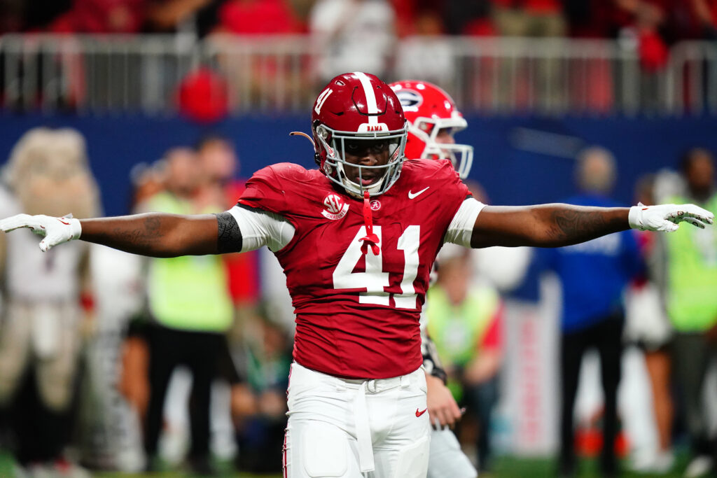 Chris Braswell (red helmet, red jersey, white pants), stands with both arms out