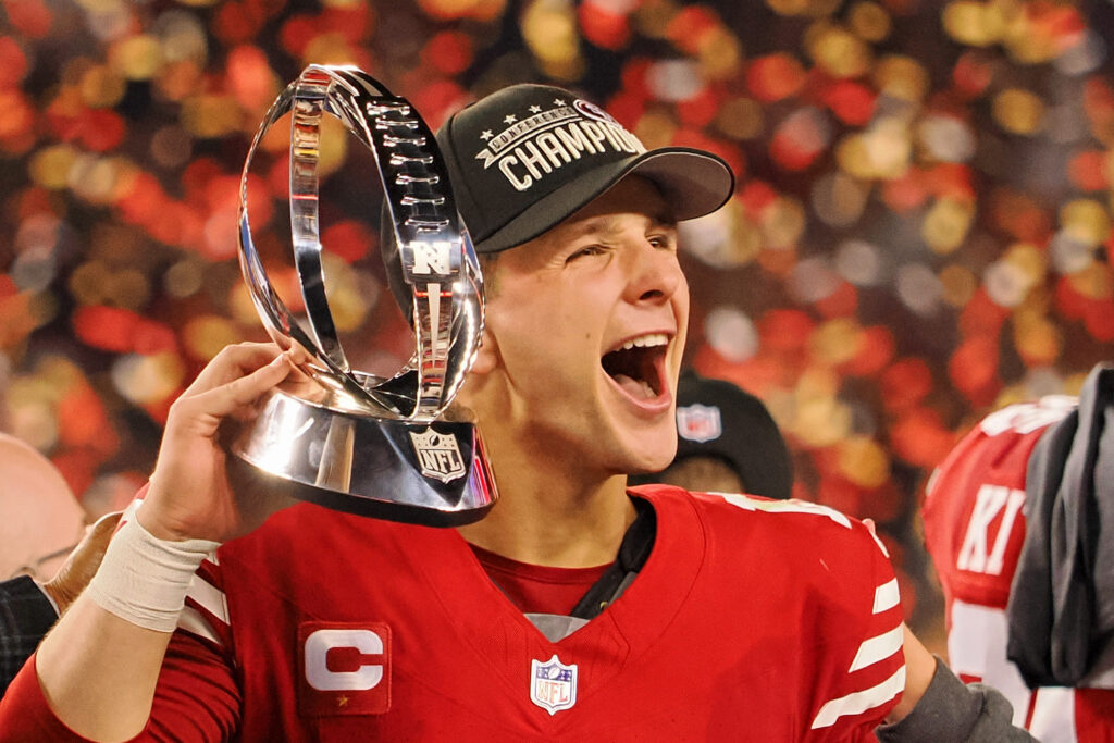 Brock Purdy celebrates amid confetti while holding the NFC Conference Champions trophy