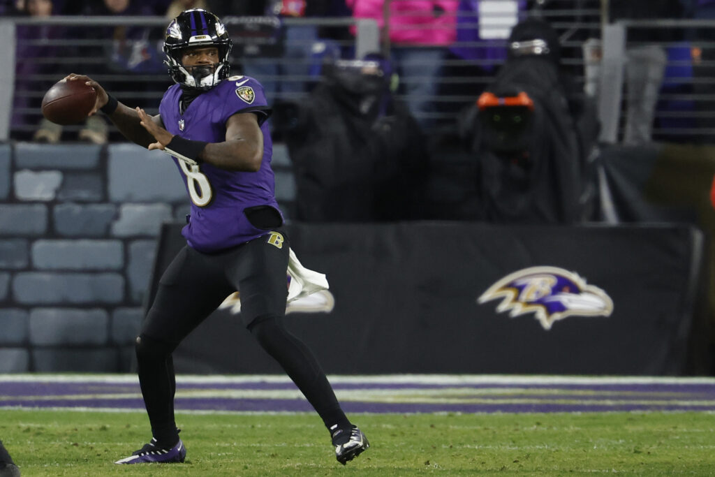 Lamar Jackson throwing the ball (purple uniform, black pants) with no one around him on the field