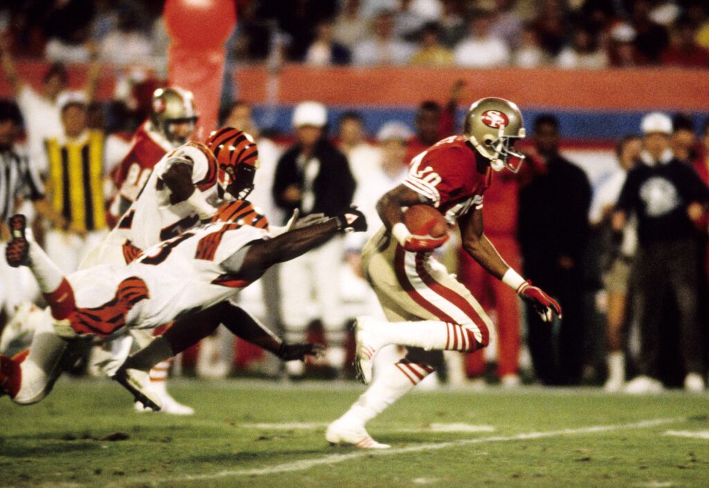 Jerry Rice runs with the ball while outstretched Bengals defenders try to tackle him