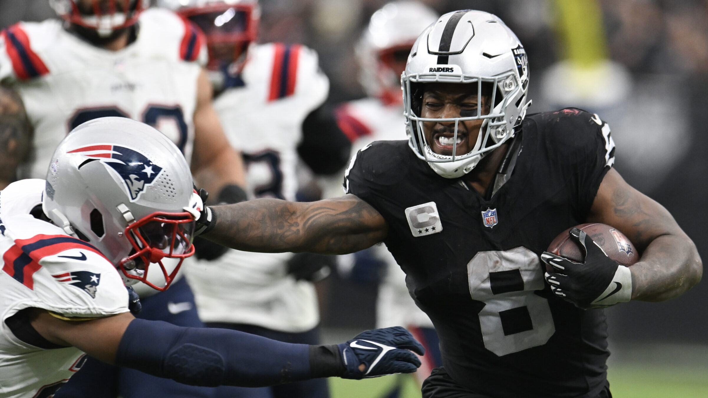 Josh Jaocbs stiff-arms a Patriots defender