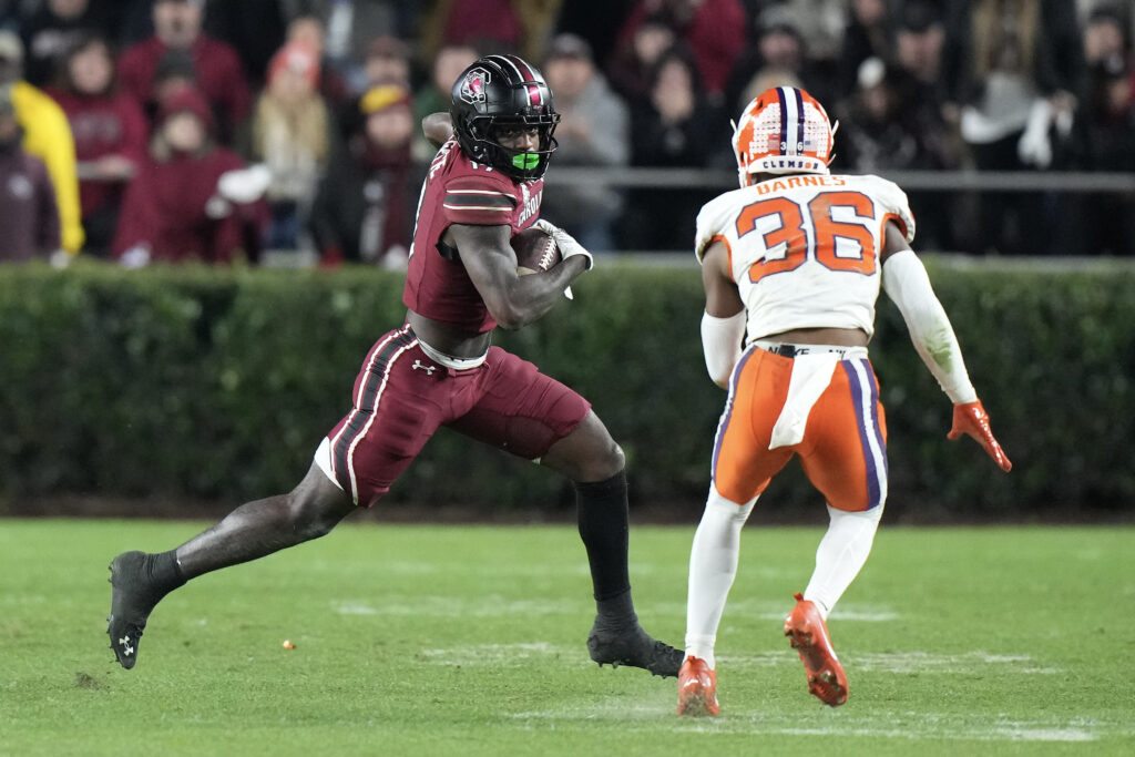 Xavier Legette, in a dark red uniform, runs with the ball with a Clemson defender closing in