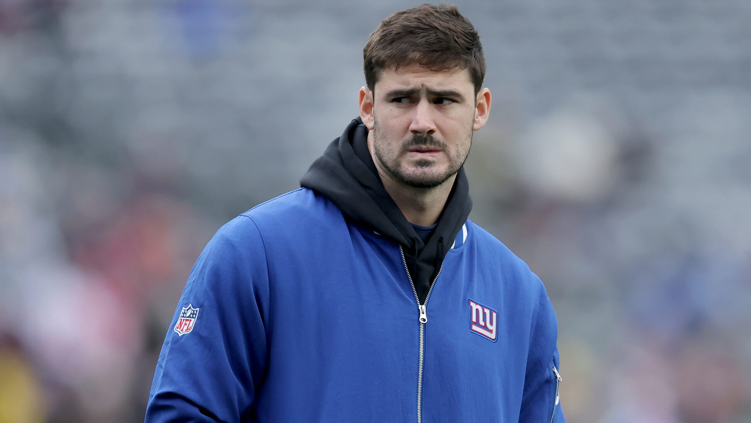 Giants QB Daniel Jones stands on the sidelines in a windbreaker