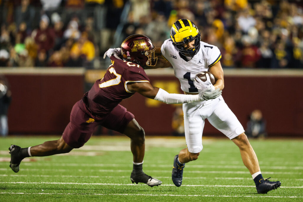 Tyler Nubin, in maroon, gets his arms around a Michigan wide receiver