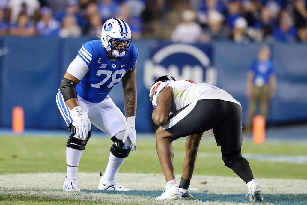 BYU offensive lineman Kingsley Suamataia towers over a Texas Tech defender in his three-point stance at the line of scrimmage