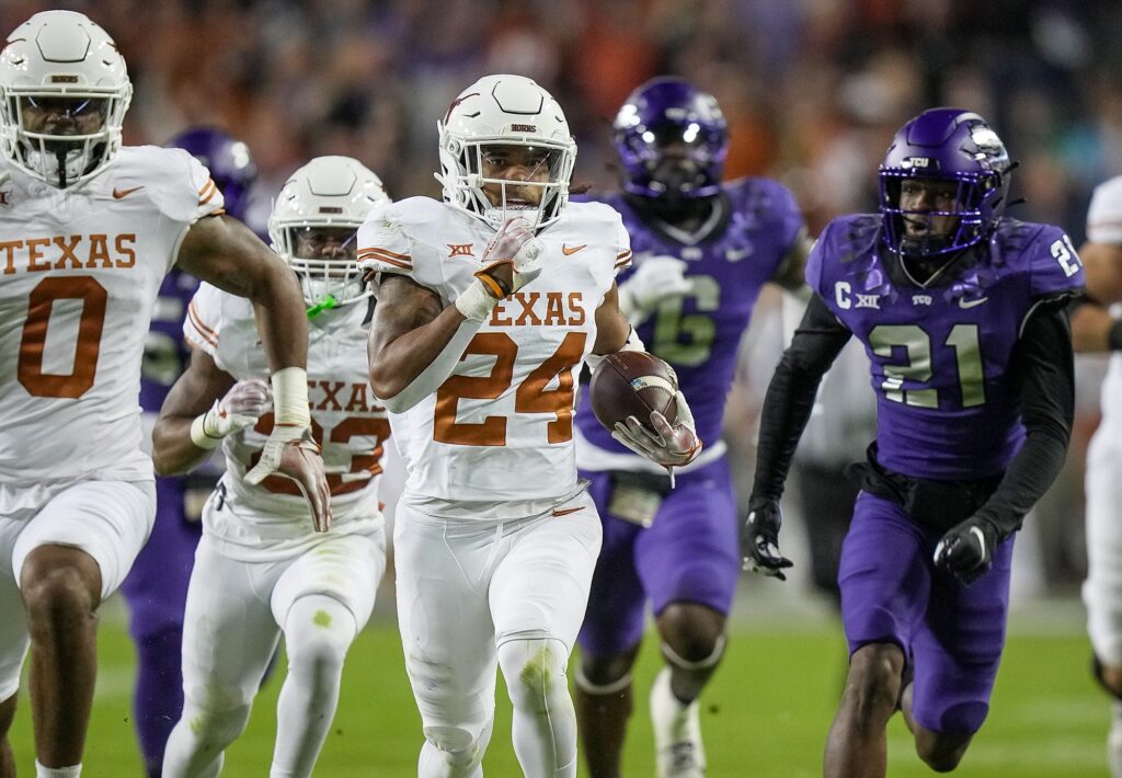 Texas running back Jonathon Brooks, in all white, runs away from a trailing pack of players dressed in white and in purple