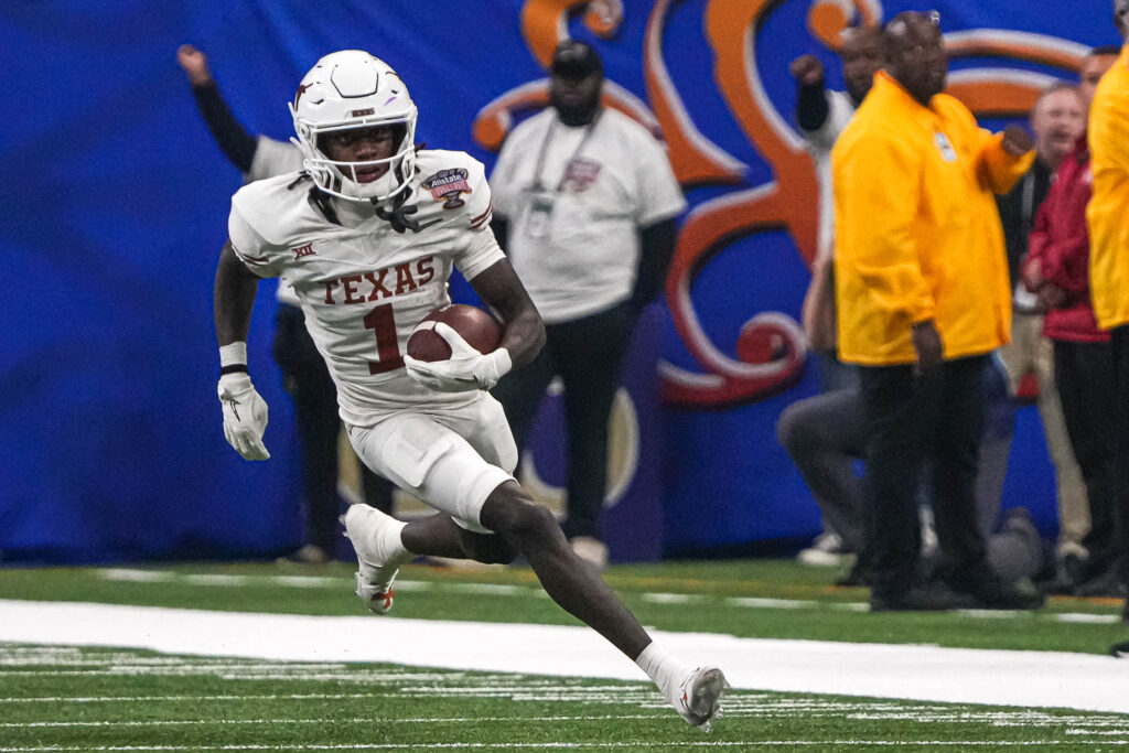 Kansas City Chiefs wide receiver Xavier Worthy (in an all-white look) runs along the sideline while carrying the ball.