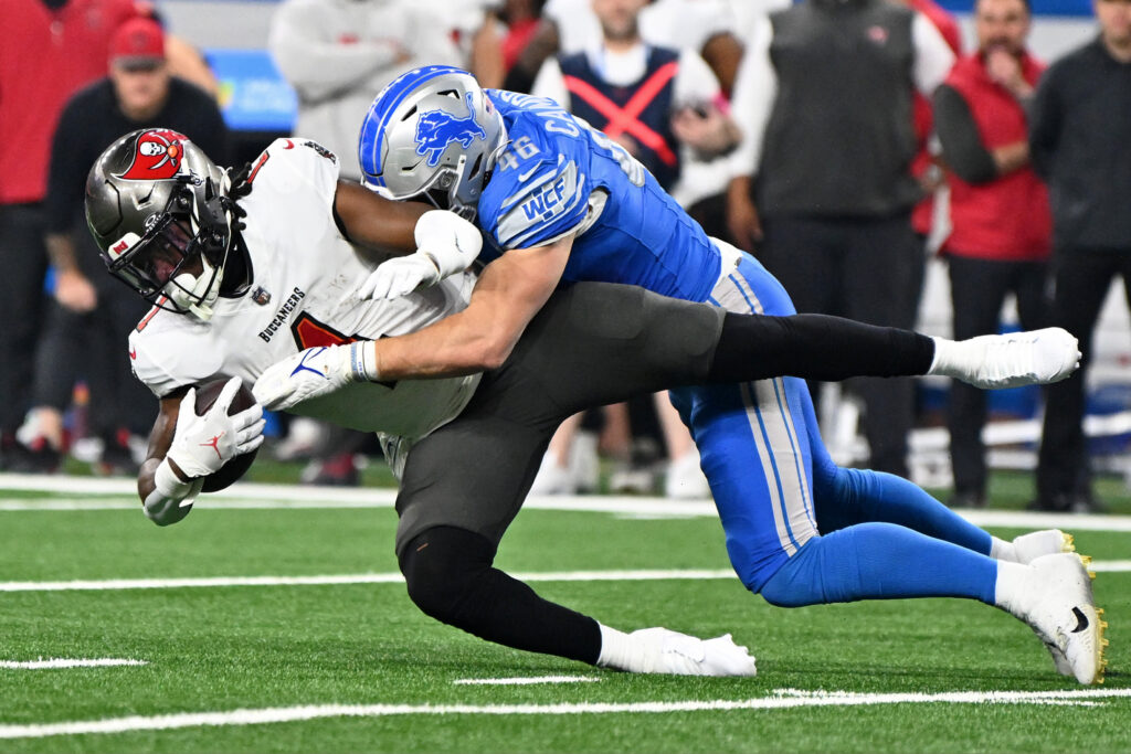 Jack Campbell, in a light blue uniform, tackles a Tampa Bay running back