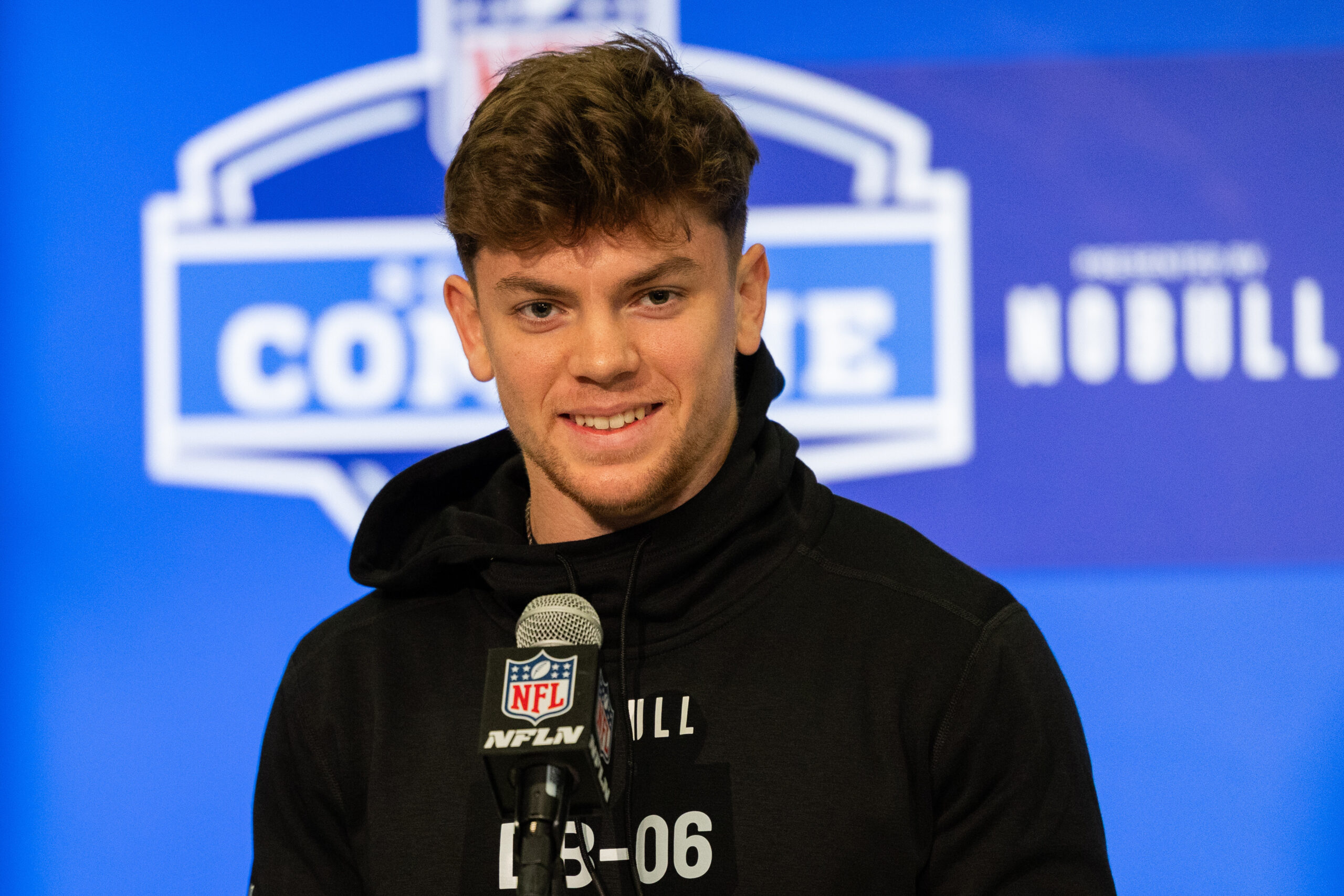 Upper-body image of Cooper DeJean in front of a microphone at the combine in front of a blue background