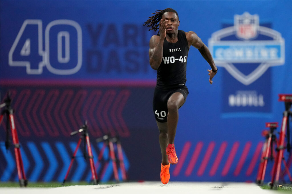 Xavier Worthy, in a black uniform and neon orange shoes, runs at the NFL Combine