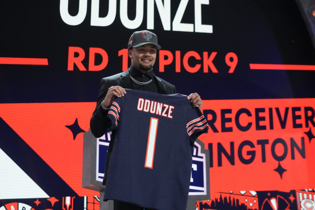 Chicago Bears wide receiver Rome Odunze holds up his new jersey on the stage of the draft