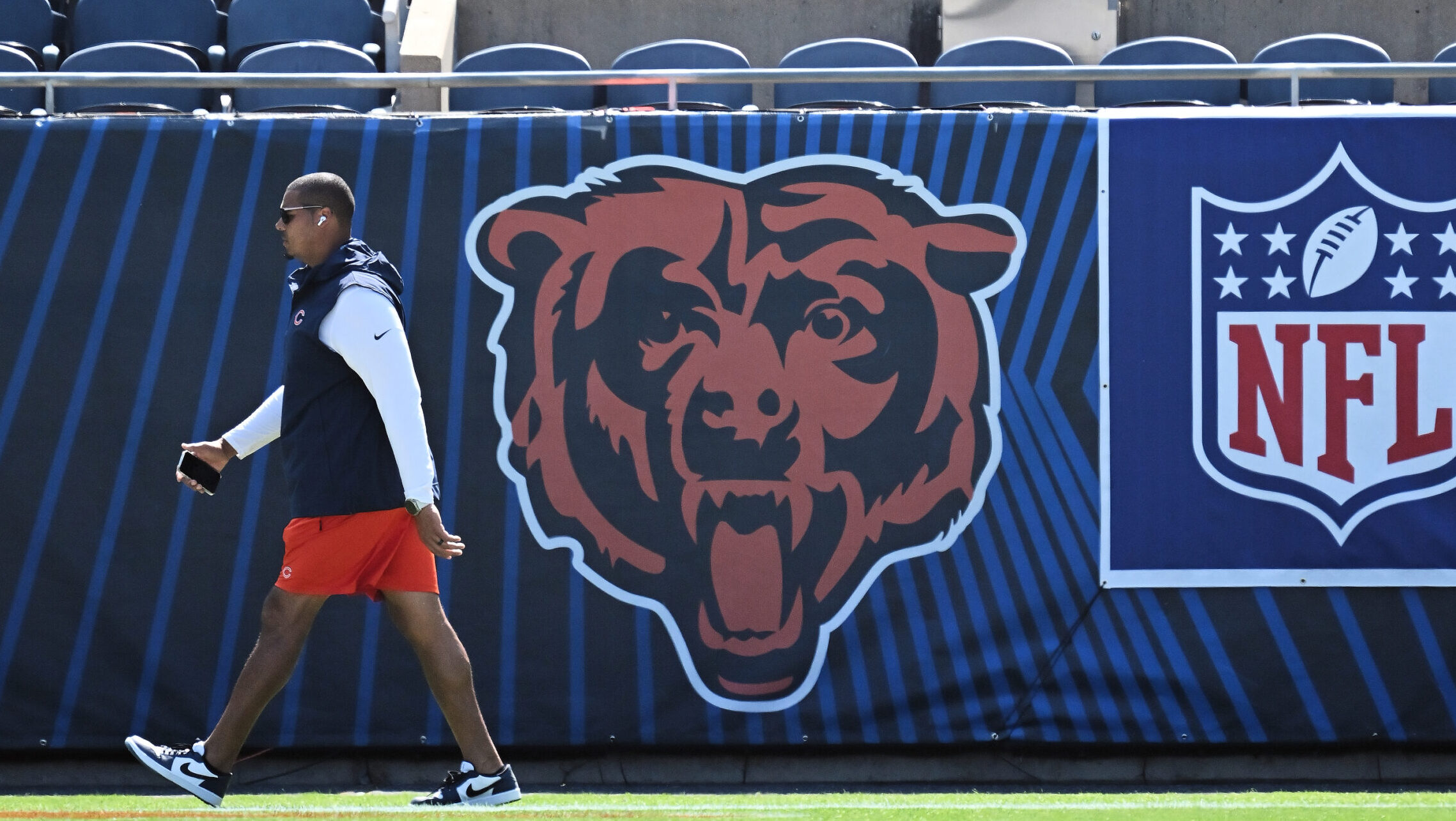 Bears GM Ryan Poles walks by the Bears logo on the field