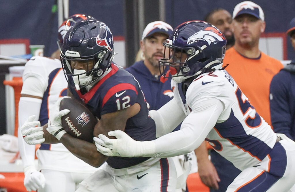 Denver Broncos edge rusher Baron Browning (white jersey, navy helmet) wraps up WR Nico Collins