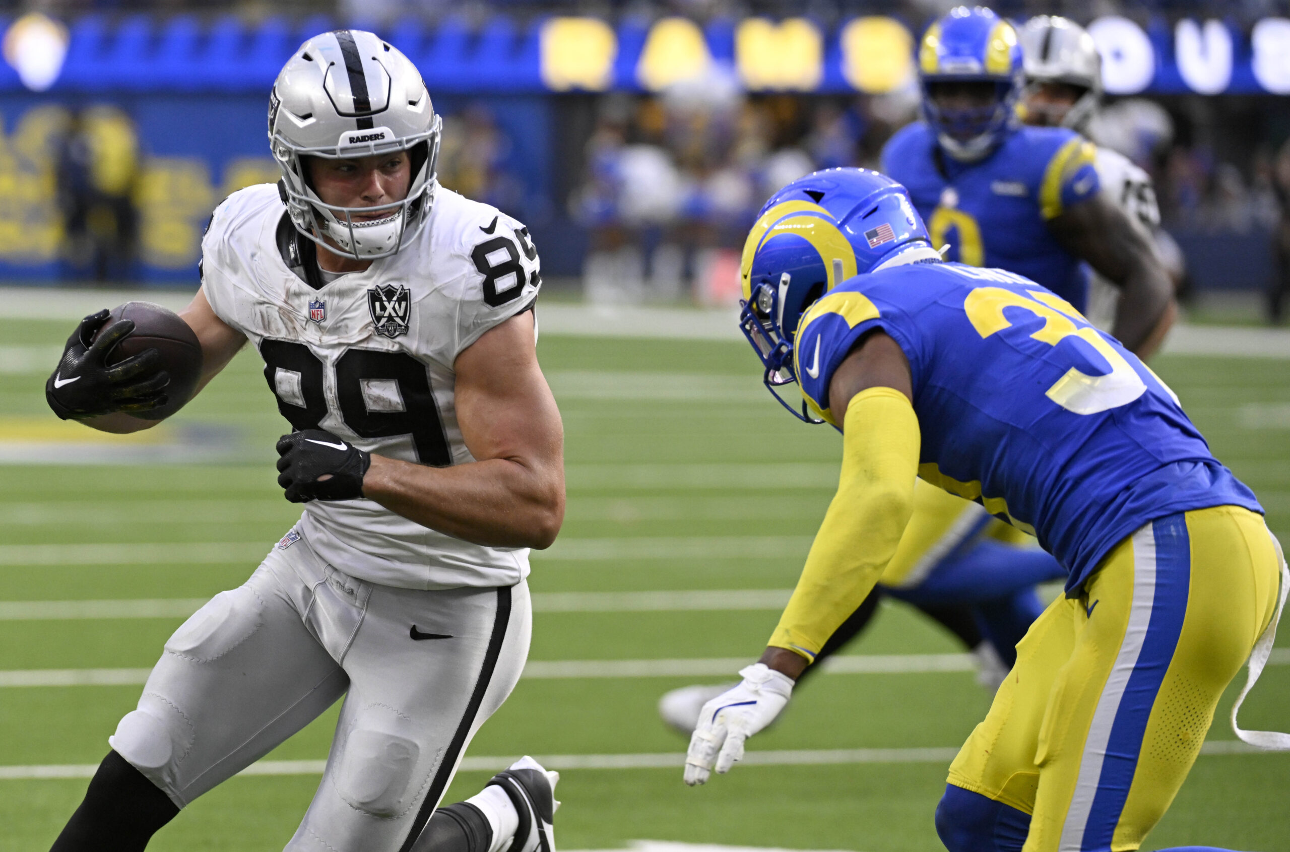 Las Vegas Raiders tight end Brock Bowers (89) braces for contract with Los Angeles Rams safety Quentin Lake (37) during the second half at SoFi Stadium.