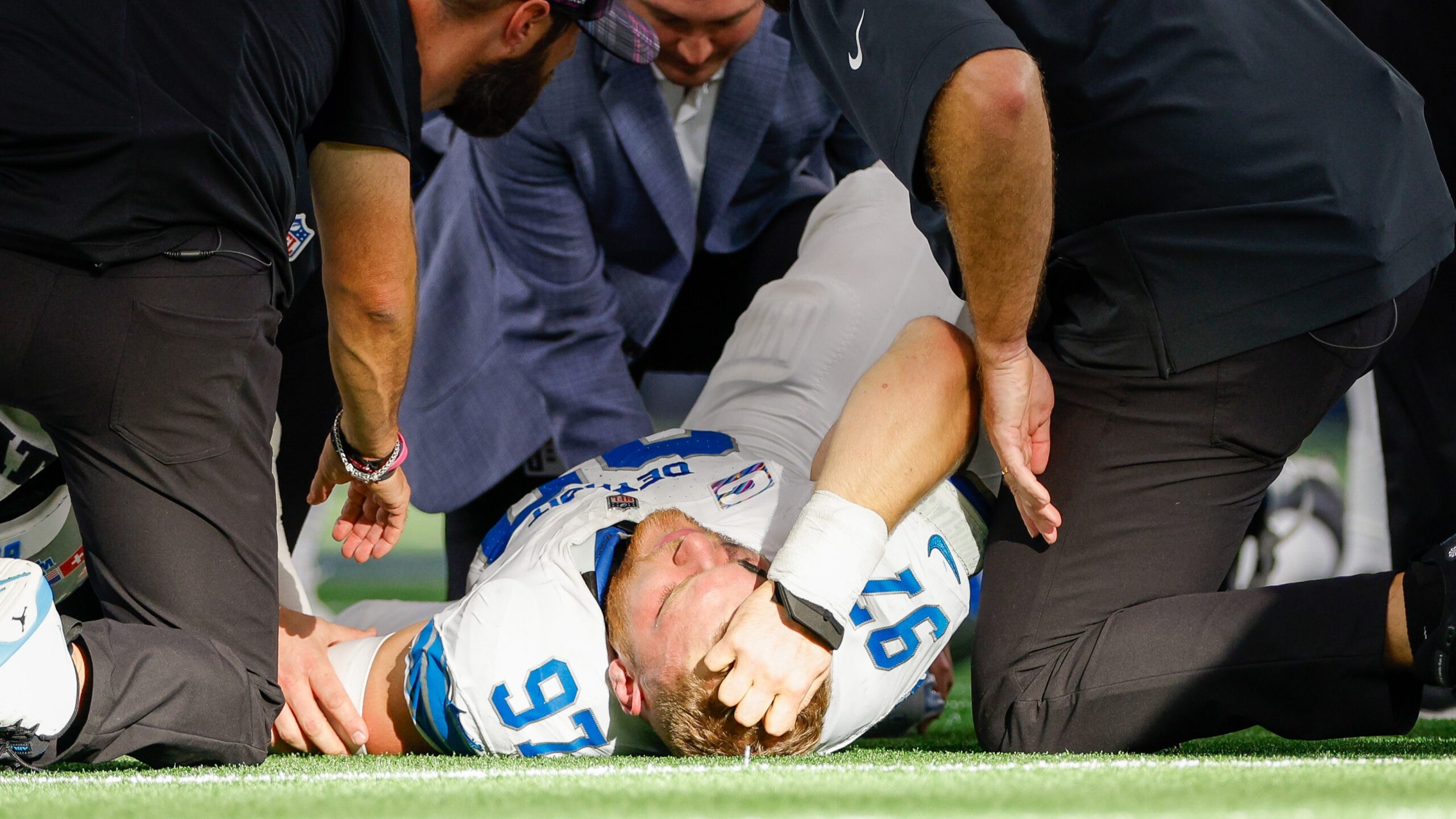 Aidan Hutchinson lays on the field flanked by trainers after fracturing his tibia.