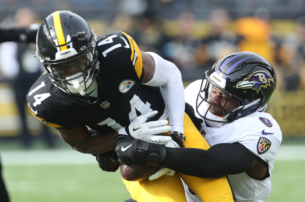 Pittsburgh Steelers wide receiver George Pickens (14) runs after a  catch as Baltimore Ravens linebacker Roquan Smith (0) defends during the first quarter at Acrisure Stadium.