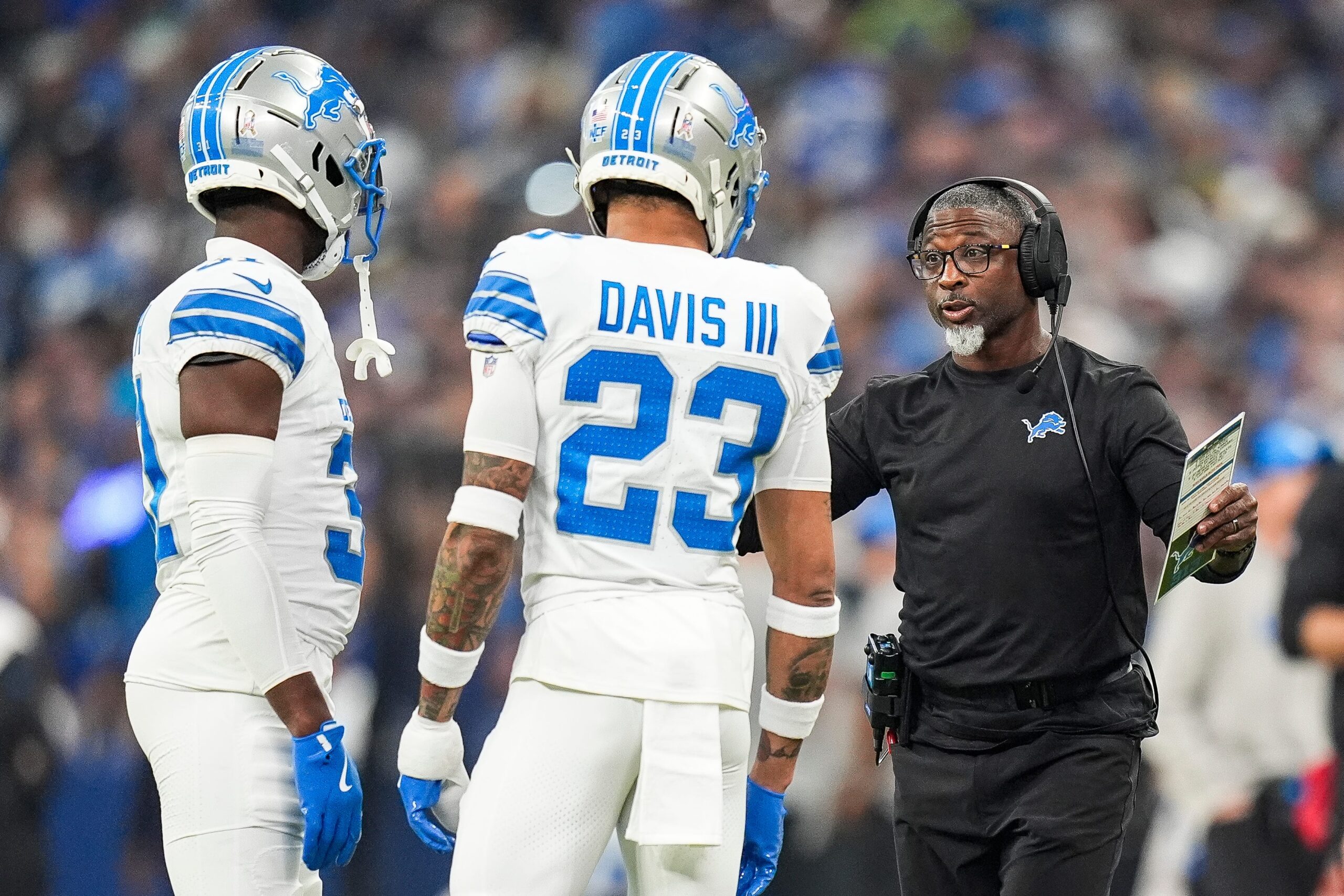 Detroit Lions defensive coordinator Aaron Glenn, right, talks to safety Kerby Joseph (31) and cornerback Carlton Davis III (23) during the first half against Indianapolis Colts at Lucas Oil Stadium in Indianapolis, Ind.