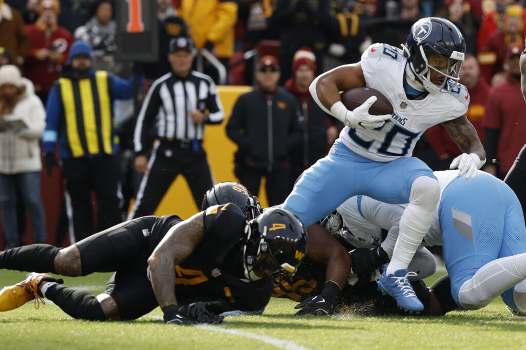 Tennessee Titans running back Tony Pollard (20) carries the ball as Washington Commanders linebacker Frankie Luvu (4) attempts the tackle during the first quarter at Northwest Stadium.