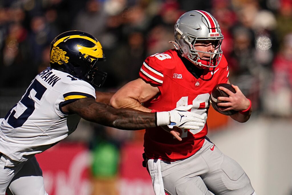 Ohio State Buckeyes quarterback Will Howard (18) runs past Michigan Wolverines linebacker Ernest Hausmann (15) during the NCAA football game at Ohio Stadium in Columbus.