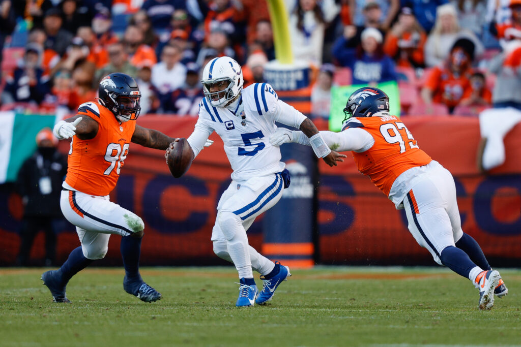 Indianapolis Colts quarterback Anthony Richardson (5) runs through the tackle of Denver Broncos defensive tackle D.J. Jones (93) and defensive end John Franklin-Myers (98) in the second quarter at Empower Field at Mile High.