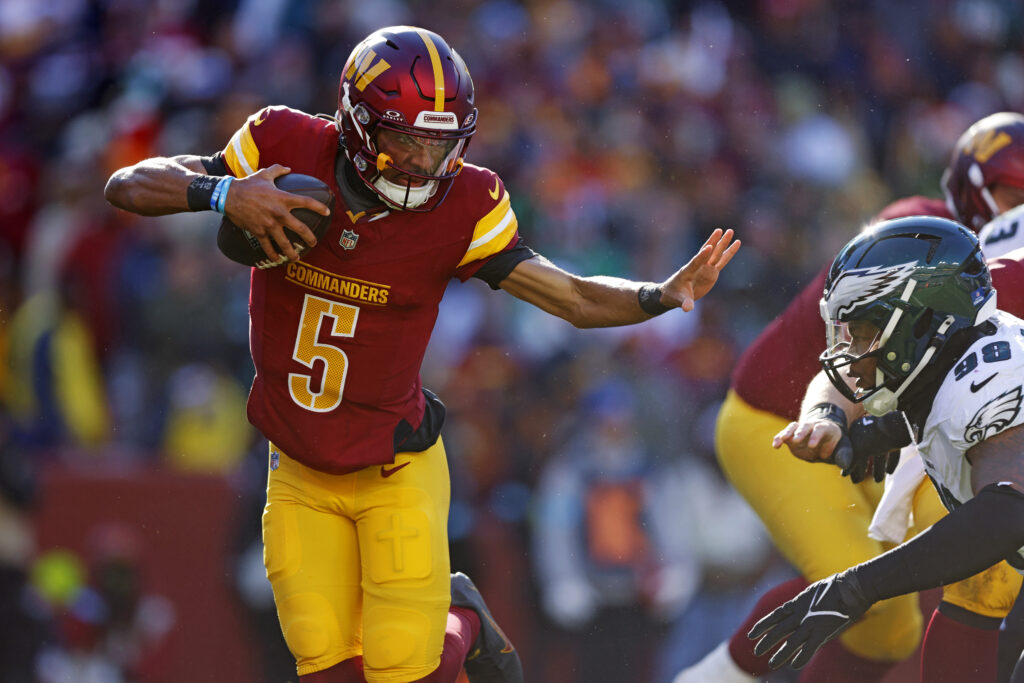 Washington Commanders quarterback Jayden Daniels (5) runs the ball against Philadelphia Eagles defensive tackle Jalen Carter (98) during the first quarter at Northwest Stadium.